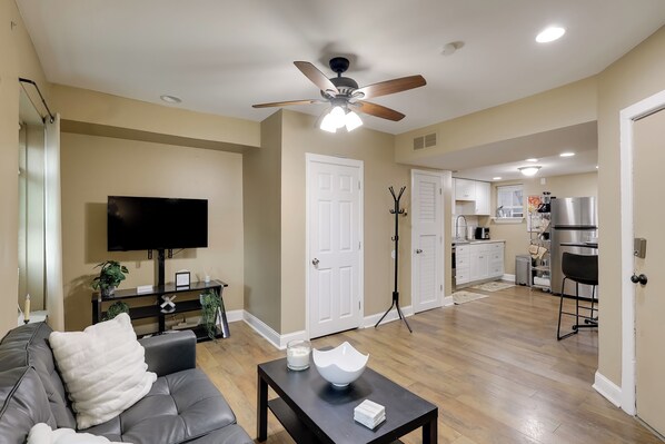 A modern living room with a grey sofa, a coffee table, and a TV. A ceiling fan and recessed lighting are visible. - 1 Mi to Dtwn Wilmington: Convenient + Cozy Home! (Wilmington)
