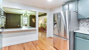 A modern kitchen with stainless steel appliances, wooden flooring, and a view into a dining area. - Bike, Hike & Unwind at Doodle Trailside Retreat (Pickens)