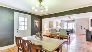 A dining area with a wooden table and chairs, a chandelier, and a view into the living room. - Bike, Hike & Unwind at Doodle Trailside Retreat (Pickens)
