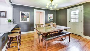 A dining area with a wooden table, benches, and a chandelier. - Bike, Hike & Unwind at Doodle Trailside Retreat (Pickens)