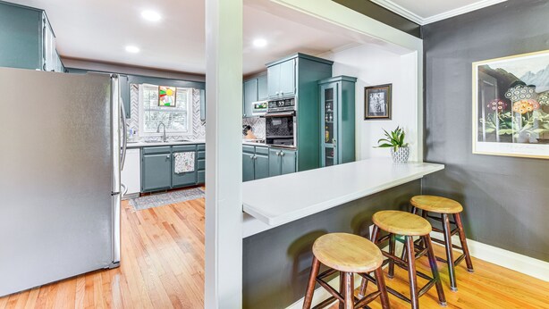A modern kitchen with a refrigerator, cabinets, and a bar area with stools. - Bike, Hike & Unwind at Doodle Trailside Retreat (Pickens)