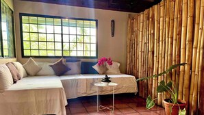 A room with a bed, a small table with a flower, and a bamboo wall. - Mi Zaru Sea View Animal Paradise (Quepos)