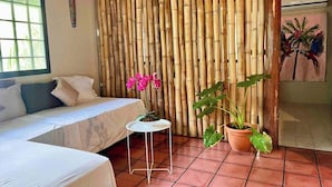 A room with a bed, a small table, and two potted plants. - Mi Zaru Sea View Animal Paradise (Quepos)