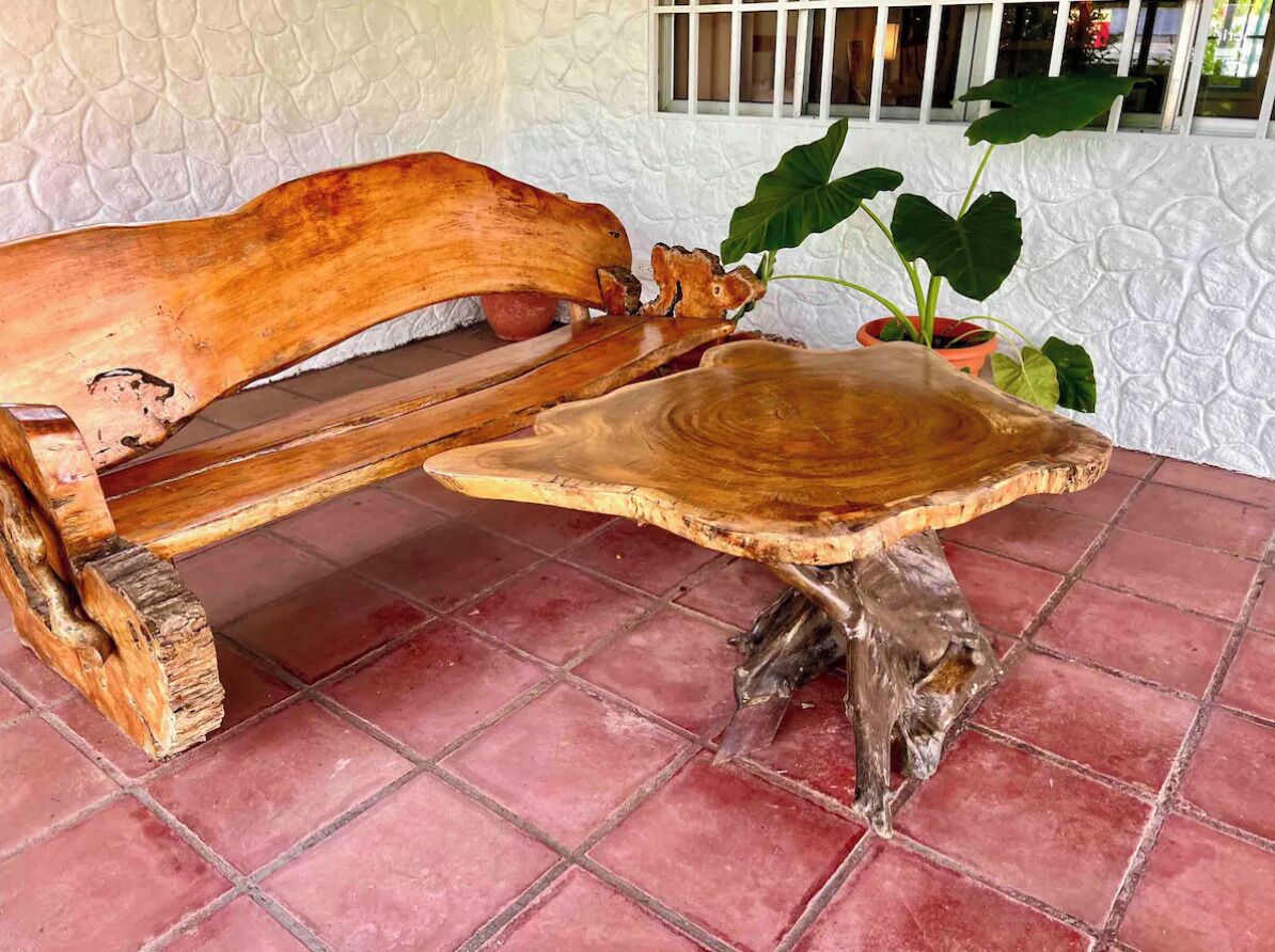 A rustic wooden bench with a unique table design, set on a red-tiled floor.