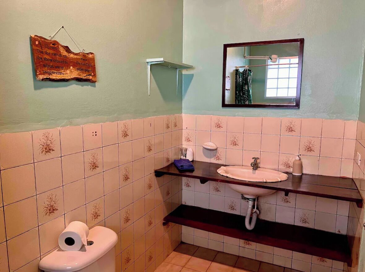 A bathroom with a toilet, sink, and mirror.