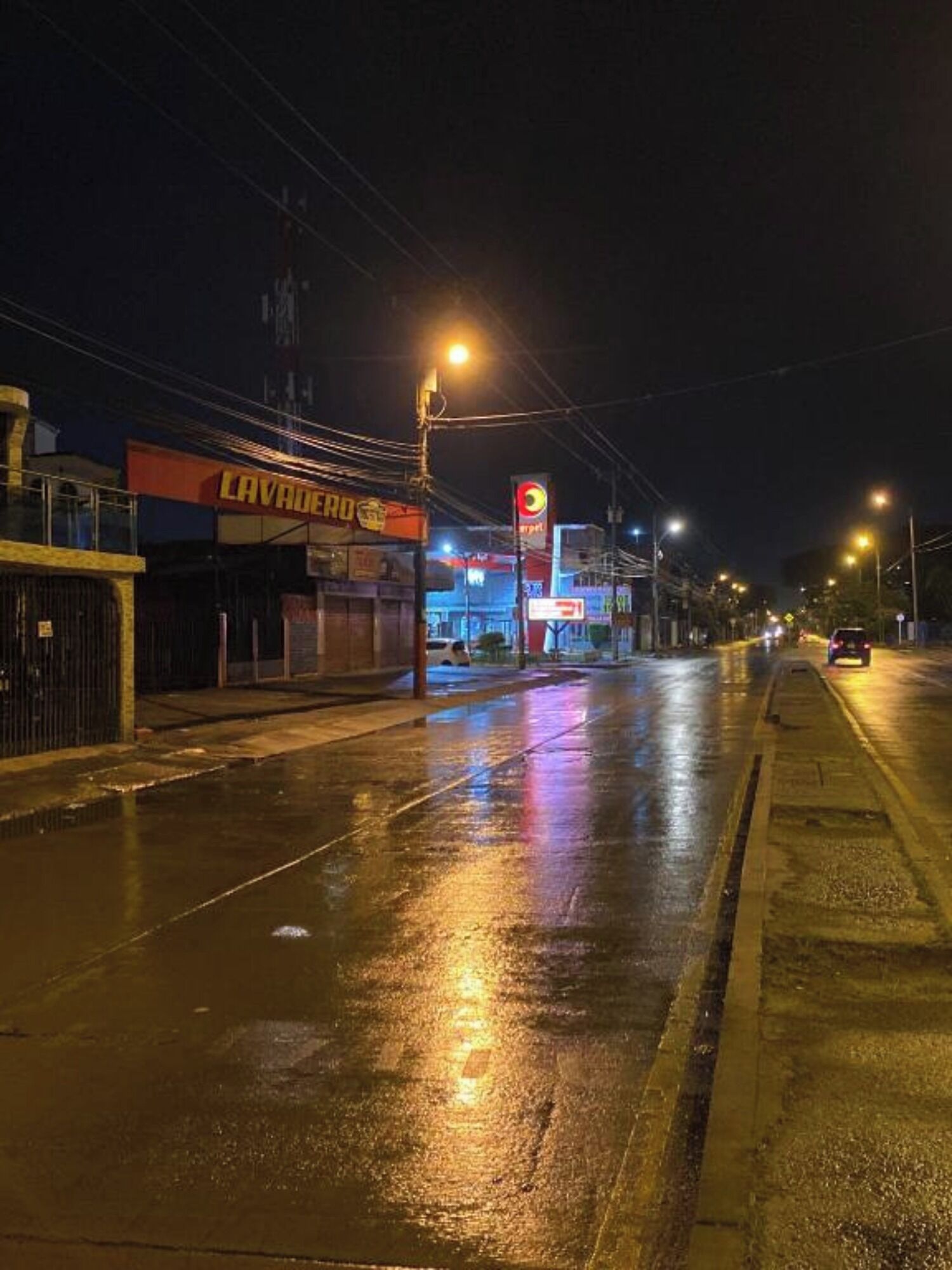 A street at night with wet pavement reflecting street lights.