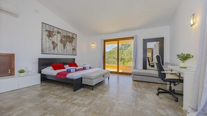 A bedroom with a large bed, a desk, and a view of a balcony. - Villa Es Garrover (Alcúdia)