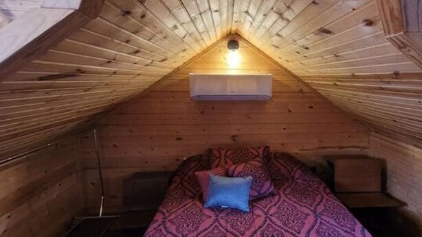 Un dormitorio acogedor en el ático, con techo inclinado, una cama individual y un ventanal pequeño.
