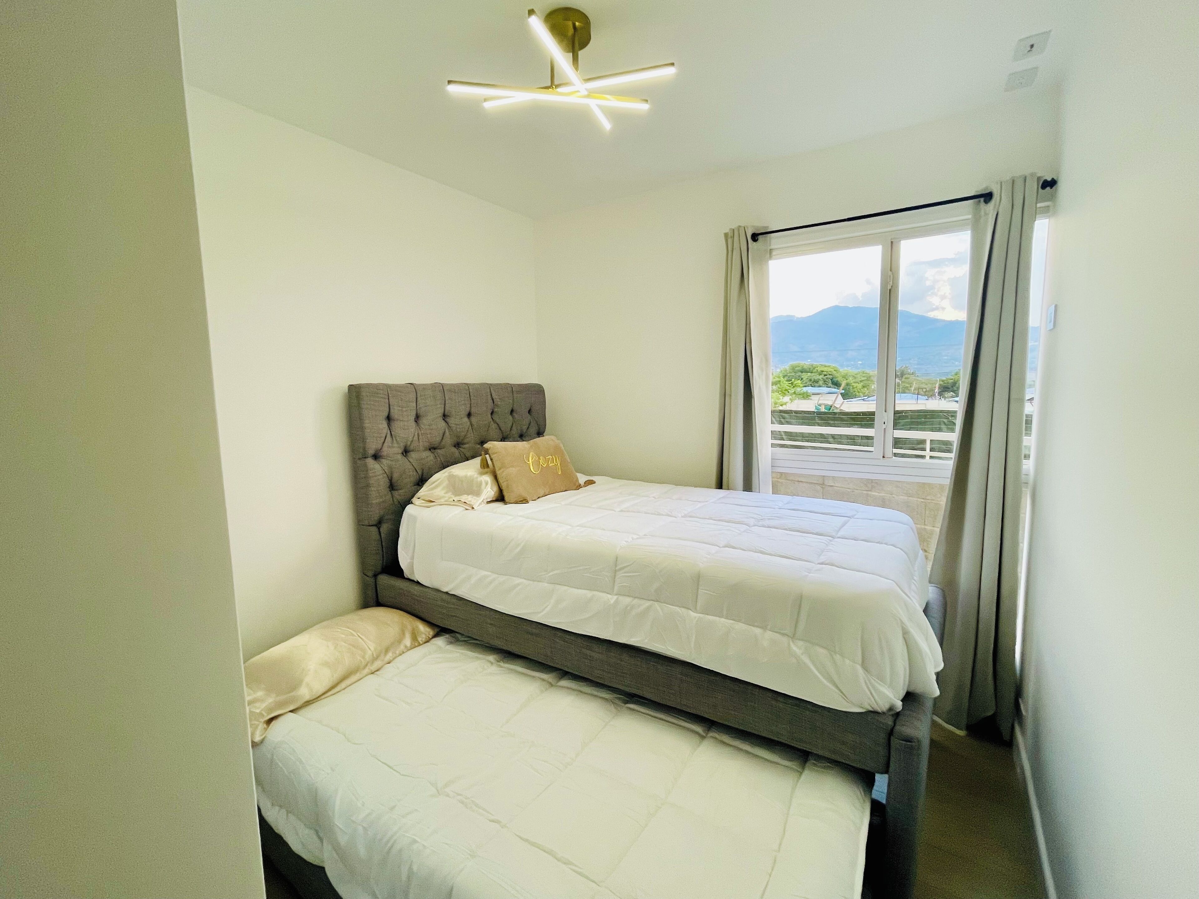 A bedroom with a bed, a smaller bed, and a view of the outdoors.