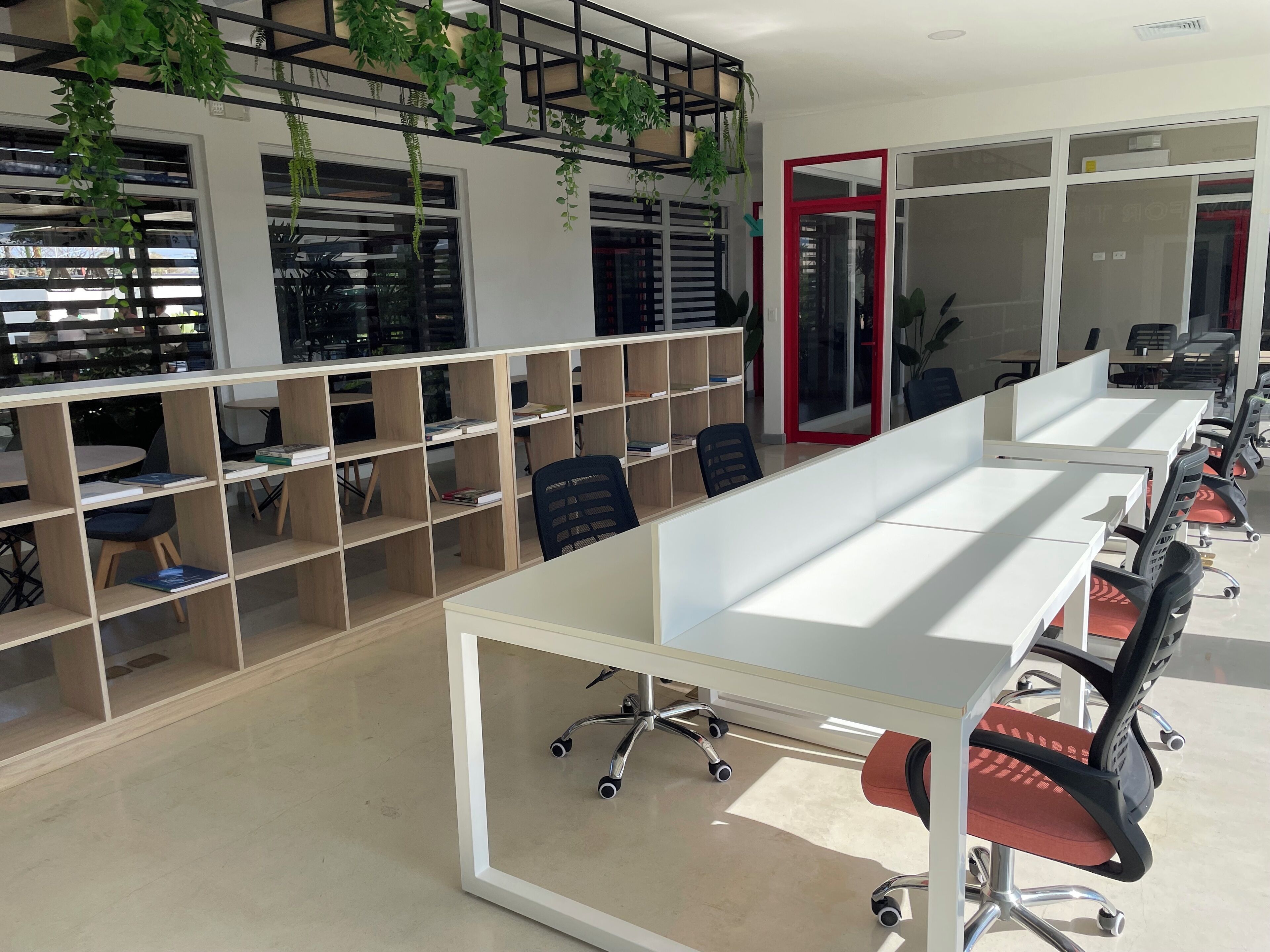 A modern office space with white desks, black office chairs, and wooden shelving units.
