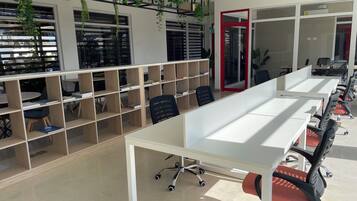 A modern office space with white desks, black office chairs, and wooden shelving units.