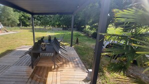 Un espace extérieur abrité, doté d’une terrasse en bois, d’une table et de chaises.