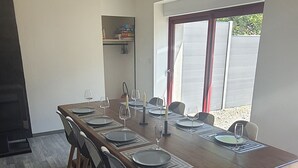 Un coin repas avec une longue table en bois, dressée pour six personnes, et agrémentée d’assiettes, de verres et de couverts.