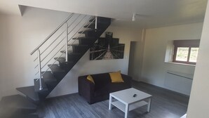 Un salon moderne avec un escalier, un canapé, une table basse et un tableau au mur.
