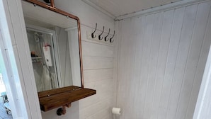 Un baño pequeño con lavamanos, espejo y retrete blancos.