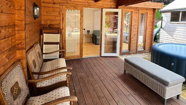 Un área de estar al aire libre techada, con bancos de madera y piso estampado.