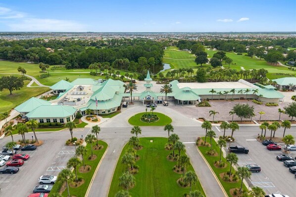 Un parcours de golf doté d’un club-house, d’un parking et entouré de verdure.