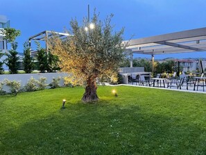 Un espace extérieur bien aménagé, agrémenté d’un arbre, d’une pergola et de coins salon.