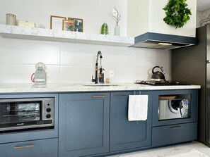 Una cocina moderna con horno empotrado, hervidor y cocina a gas.