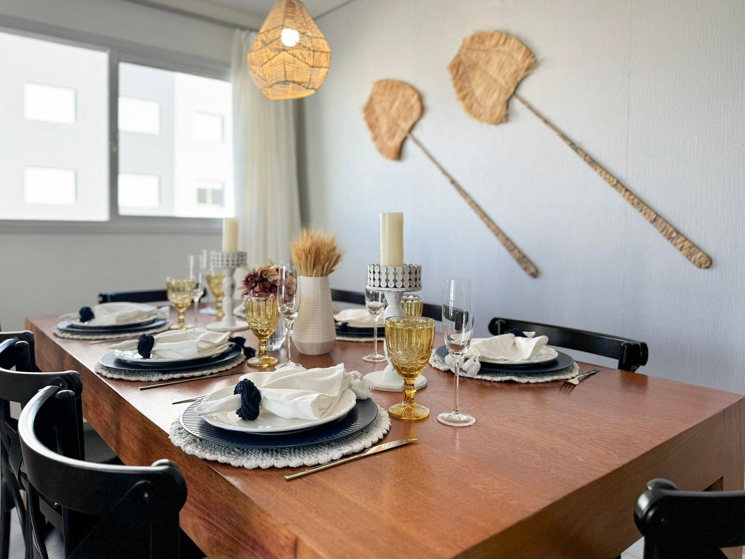 Une table à manger dressée avec des assiettes, des verres et des couverts, agrémentée d’une bougie et d’objets décoratifs.