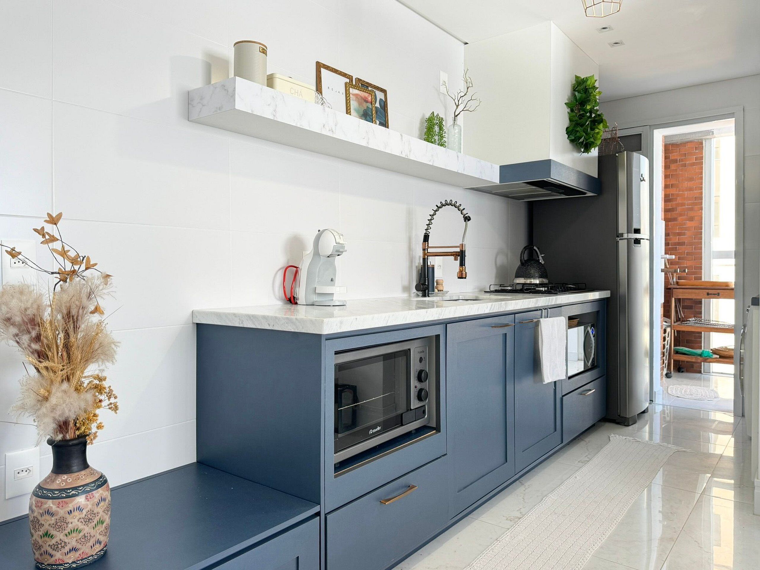 A modern kitchen with a marble countertop, built-in oven, and a stainless steel refrigerator.