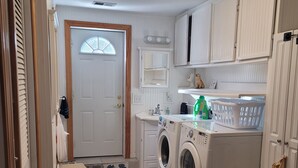 A laundry room with a washing machine, dryer, and a small sink. - "Huron Winds" a charming 3-bedroom house just steps from Lake Huron in Oscoda (Oscoda)