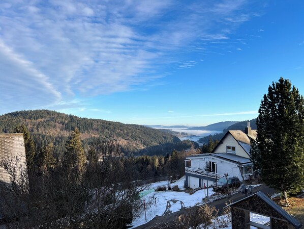 A house with a balcony overlooking a snowy landscape and forested hills. - Villa Hubertus - Panorama Apartment (Feldberg)
