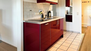 Een moderne keuken met rode kasten, een roestvrijstalen afzuigkap en een dubbele spoelbak.