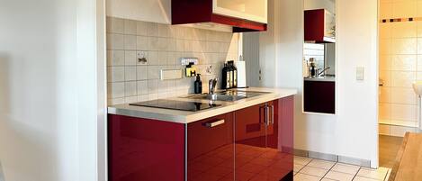 Una cocina moderna con armarios rojos, una campana extractora de acero inoxidable y un lavamanos doble.
