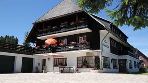 Een gebouw met twee verdiepingen, inclusief een balkon op de bovenverdieping, een bord met de tekst 'Villa Hilbertus' en een geplaveid binnenhof.