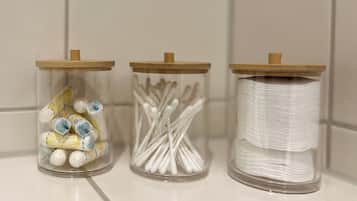 Three glass jars with wooden lids on a white tiled surface.