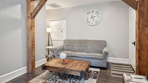 Un salon avec un canapé gris, une table basse en bois, un globe terrestre et une horloge murale.