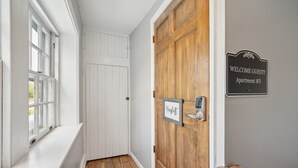 Un corridoio con una porta in legno, una targa di benvenuto e una targhetta con il nome.