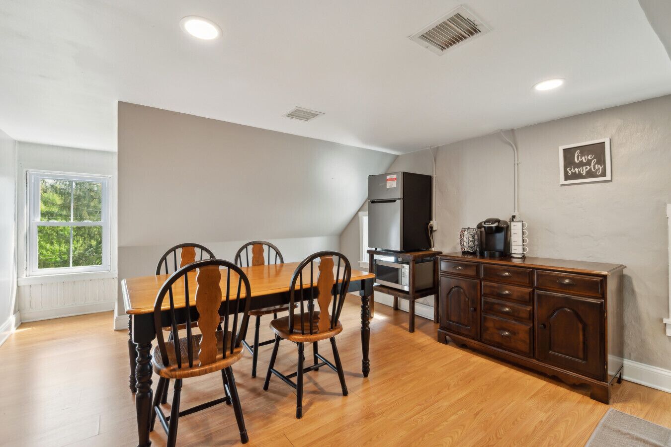 A spacious kitchen with a dining area, wooden cabinets, and a refrigerator.
