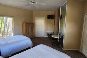 A hotel room with two beds, a ceiling fan, a TV, a small table, and a chair. - Right Direction Rentals Studio Villa 9981 (Port St. Lucie)