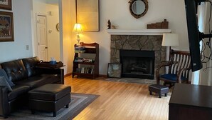 Una sala de estar con chimenea, un sofá, una mesa de centro y un televisor.