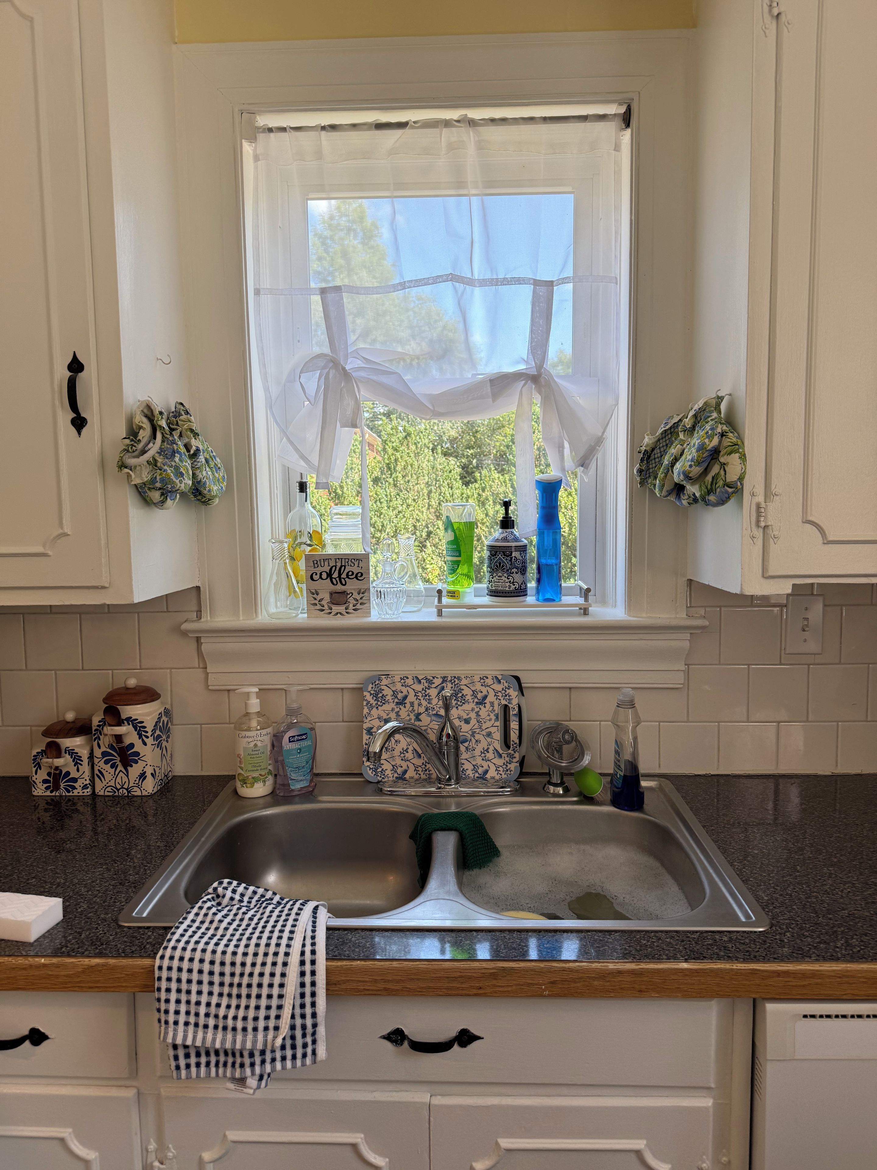 Una cocina con ventana, un lavamanos y varios utensilios.