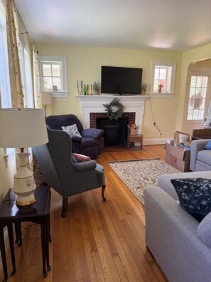 A living room with a fireplace, a television, and a sofa. - She’s a Brick House - 4 Bed 2 Bath Cozy Cottage in Town of Orange, Virginia (Orange)