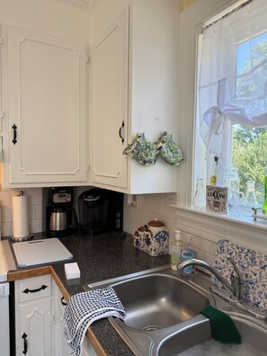 A kitchen with white cabinets, a stainless steel sink, and a window with sheer curtains. - She’s a Brick House - 4 Bed 2 Bath Cozy Cottage in Town of Orange, Virginia (Orange)