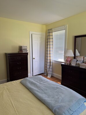 A bedroom with a bed, a dresser, a mirror, a window with blinds, and a door. - She’s a Brick House - 4 Bed 2 Bath Cozy Cottage in Town of Orange, Virginia (Orange)