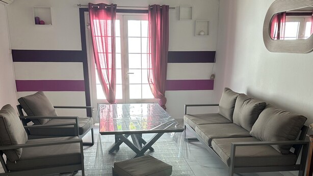 A modern living room with a glass-top coffee table, two sofas, and a small ottoman. - Lovely 160 m2 house with sea view (Vieux-fort)