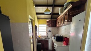 A kitchen with a tiled floor, wooden cabinets, a white refrigerator, and a hanging light fixture. - Lovely 160 m2 house with sea view (Vieux-fort)