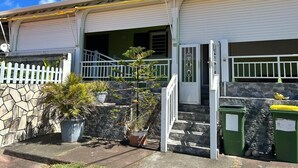 A two-story house with a stone wall, a white picket fence, and a small staircase leading to the front door. - Lovely 160 m2 house with sea view (Vieux-fort)