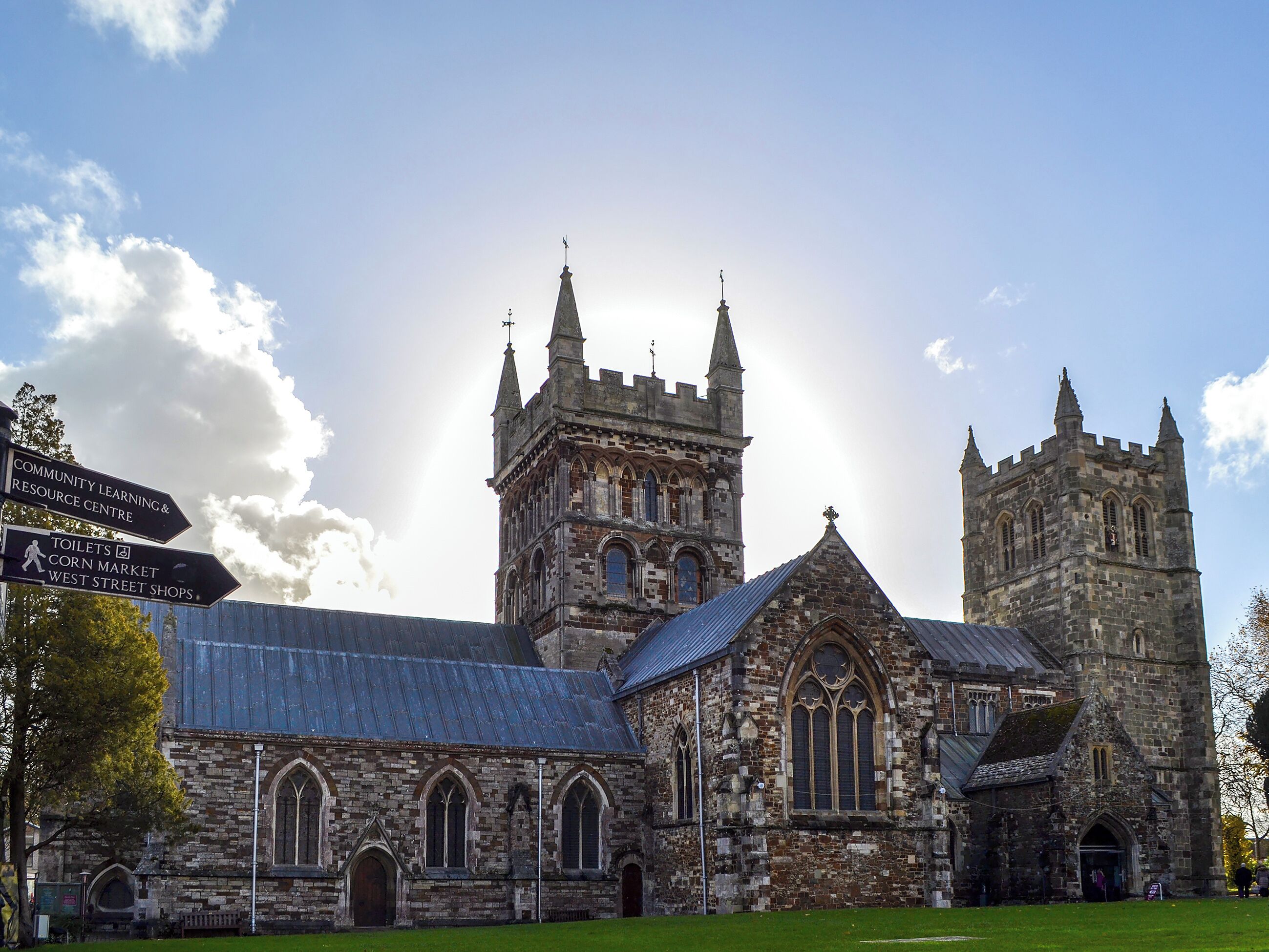 Une église historique, reconnaissable à son imposant clocher, à sa grande fenêtre en arc de cercle et à un panneau indiquant les commodités à proximité, comme des toilettes et un marché.