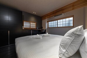 Une chambre à coucher moderne, dotée d’un grand lit, de lambris en bois foncé et offrant une vue sur l’extérieur par une fenêtre.