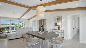Een modern interieur met een eethoek, witte meubels en een groot raam met uitzicht op een tuin.