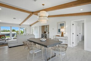 Un intérieur moderne avec un coin repas, des meubles blancs et une grande fenêtre donnant sur un jardin.