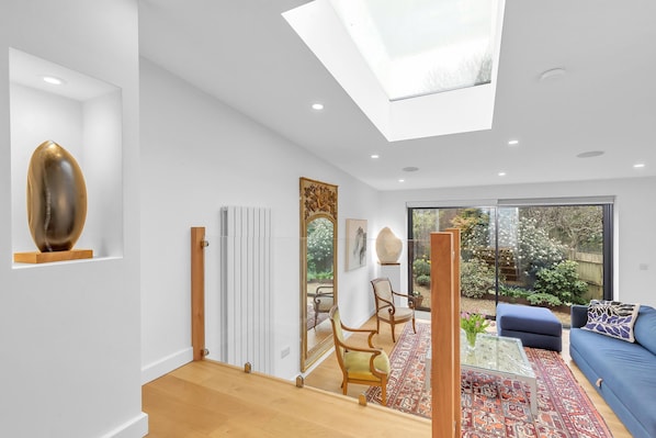 A modern living room with a skylight, a blue sofa, and a large mirror.