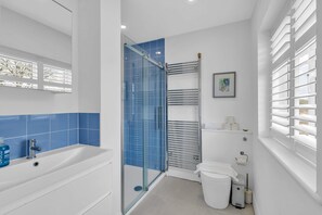 Une salle de bain moderne avec une douche à parois de verre, une baignoire blanche et des toilettes.