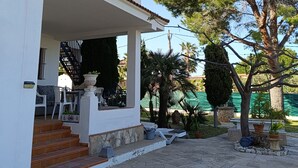 A two-story house with a covered patio, stone flooring, and outdoor furniture. - Villa Teresa (L´Ametlla de Mar)